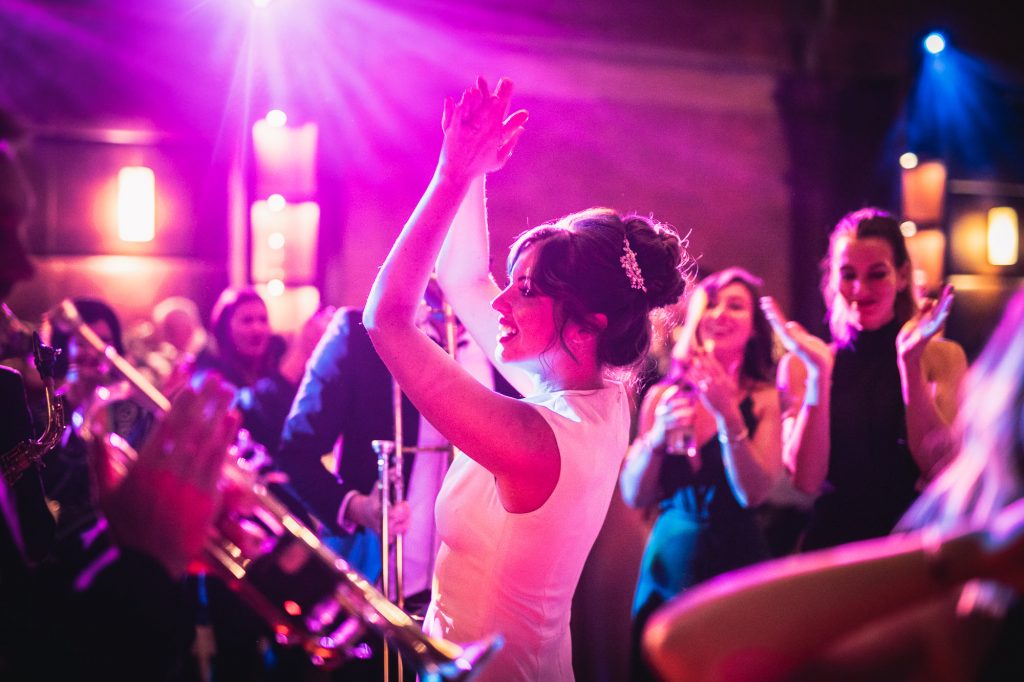 Guide To Booking Music For Your Wedding - A bride dances whilst a trumpeter plays